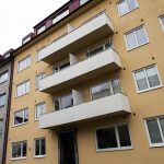 Gult lägenhetshus med vita fönster och vita balkonger