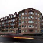 Brunt tegelhus med vita fönster vid en bilväg