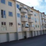 Gult lägenhetshus med balkonger och garage