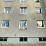 Närbild på beige lägenhetshus med vita fönster