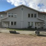 Framsidan av ett vitt lägenhetshus i trä