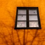 Svart fönster på ett orange hus
