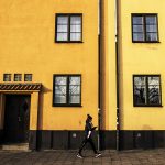 Framsidan på ett gult lägenhetshus med svarta fönster